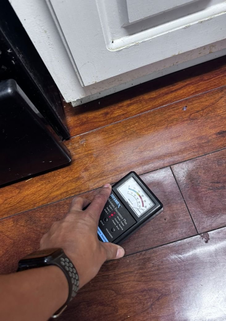 ERT technician using a moisture meter to check hidden water damage in flooring