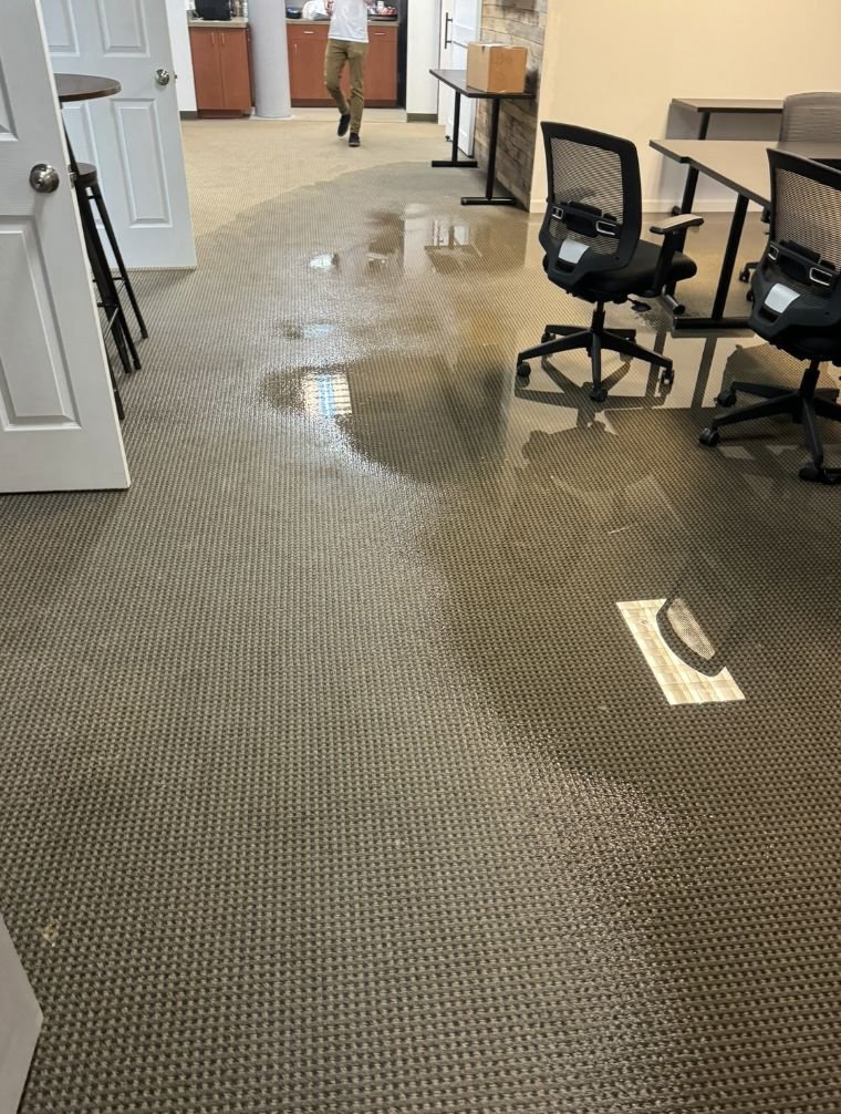 Standing water spreading across office carpet during a Charlotte NC commercial water damage call